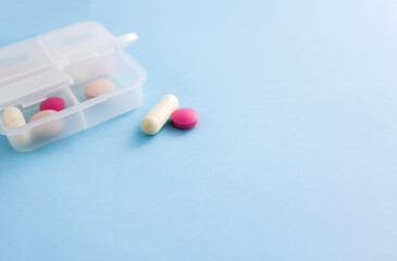 Pill box and tablets on blue background. Minimal concept of taking medications. Copy space,...
