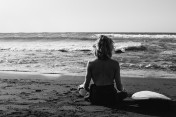 Young surfer man meditating on the beach - Healthy lifestyle concept - Black and white edition