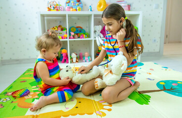 Fototapeta premium Children play together treat the bear. Selective focus.