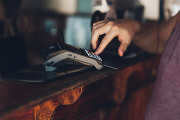 Unknown man paying with card in a store, hand putting authorization pin