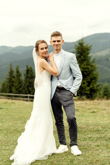 Beautiful happy smiling young couple in love hugging in the mountains, against the backdrop of a beautiful landscape. wedding day moment