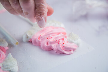 Pink meringue hats with white pompoms and brims are sprinkled with white balls on the side, against a parchment background. High quality FullHD footage