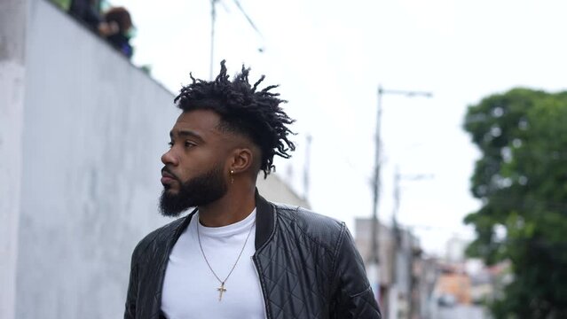 One pensive young black man walking in urban street rubbing eyes and face