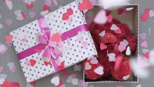 The concept of Valentine's Day. A gift in an elegant beautiful box. Stuffed bear toy. Confetti hearts fall from above. Cute and romantic picture
