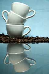 Coffee cup stack with coffee beans on reflective surface