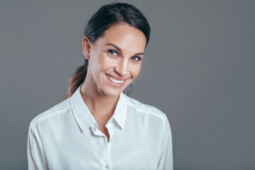 Happy young business woman ready to work posing against gray