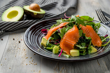 mixed salad with salmon and avocado on grey wooden table macro close up