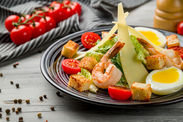 salad caesar with shrimps on plate on grey wooden table macro close up