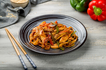 Udon noodles with chicken and vegetables on grey wooden table