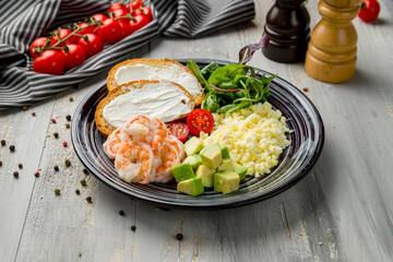 scramble with shrimp and avocado on grey wooden table