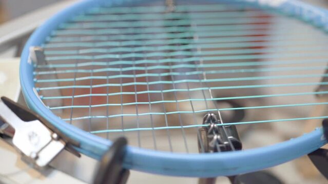 manual stringing of a tennis racket in service