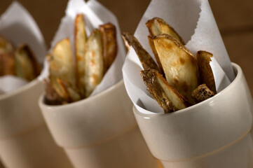 French fries, potato wedges in cup with parchment paper