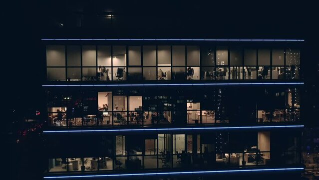 People work in Offices in a large modern business center with transparent panoramic windows. Call center managers in offices work around the clock at night. People work in modern Glass coworking.