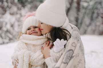 Mom and daughter in a snowy forest. Christmas theme, mom and daughter in white clothes.