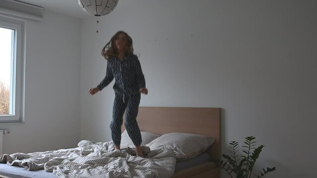 Happy teen child girl jumping fun in pajama on bed