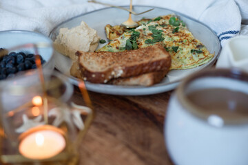 A cozy breakfast in bed set up with coffee, candle, & neutral setup