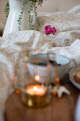 A cozy breakfast in bed set up with coffee, candle, & neutral setup