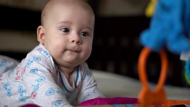 Newborn Active Baby Cute Smiling Teethless Face Portrait Early Days On Stomach Developing Neck Control. 5 Months Child In Playpen Gnaws Toys Look At Camera. Infant, Childbirth, Beginning Concept