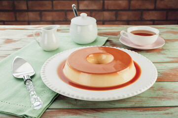 Milk pudding with caramel syrup on a white plate.