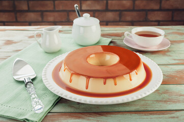 Milk pudding with caramel syrup on a white plate.