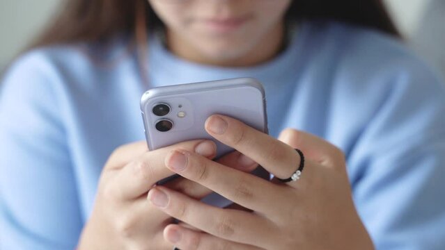 Pretty teenage girl student using texting smartphone or chat, Womans hands holding phone , typing message on mobile in the living room at home morning. Close up view. 4k footage