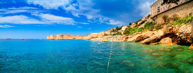 Coastal summer landscape, panorama - view of the city beach on the background of the Old Town of Dubrovnik on the Adriatic coast of Croatia © rustamank
