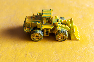 yellow toy bulldozer on yellow background
