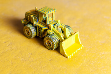 dark yellow toy bulldozer on yellow background