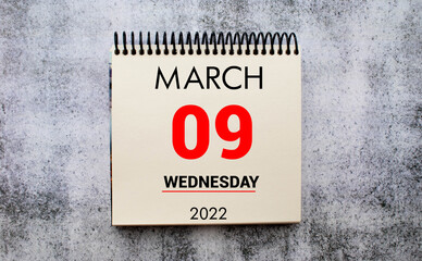 march 9. 9th day of month, calendar date. Stand for desktop calendar on beige wooden background.