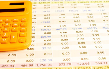 Orange calculator and pen with accounting paperwork for financial tasks