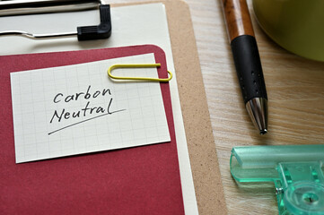 A piece of paper clipped to the edge of the red notebook has Carbon Neutral.
