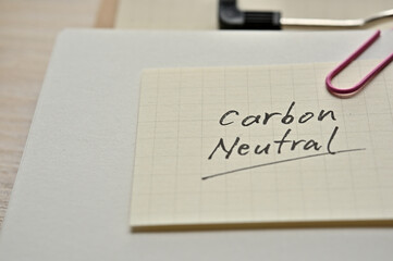 A piece of paper clipped to the edge of the notebook has Carbon Neutral.