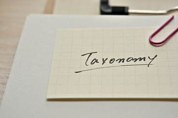 A piece of paper clipped to the edge of the notebook has Taxonomy.