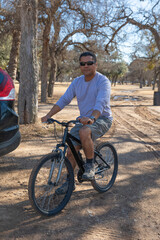 handsome middle age man riding a bike in the park at the park in the sunny day