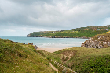 Beautiful sandy Barley Cove Beach. Ocean and green fields in the background. County Cork, Ireland. Popular tourist location with long swim area and dunes.