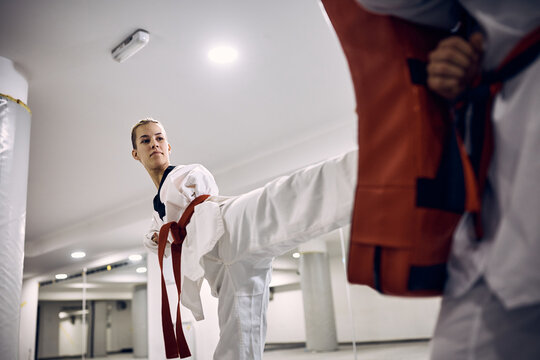 Taekwondo fighter with para-ability practices her leg kick with coach in health club.