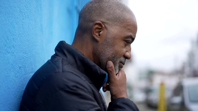 A pensive black senior man thinking about decision stading outside in street