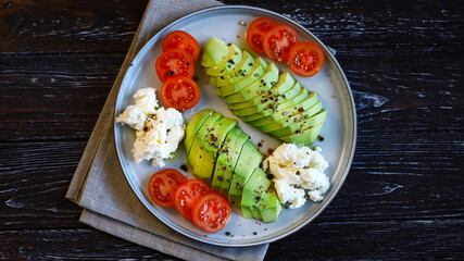 Sliced avocado with cream cheese and tomatoes on a plate. Selective focus, macro. Keto diet.
