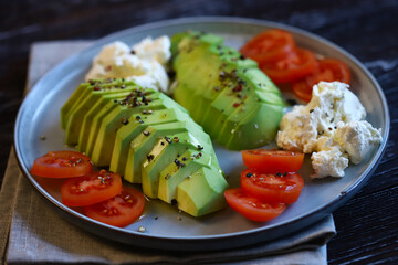 Sliced avocado with cream cheese and tomatoes on a plate. Selective focus, macro. Keto diet.