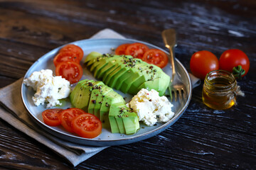 Sliced avocado with cream cheese and tomatoes on a plate. Selective focus, macro. Keto diet.