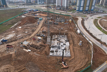 Fototapeta premium Construction site with tower cranes on formwork building construction. Foundation slab for monolithic reinforced skyscraper. First Floor Slab on buildings сonstruction. Formworks and pouring concrete.