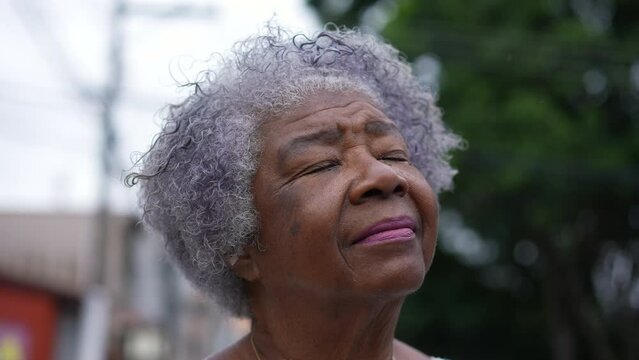 A pensive senior black woman closing eyes in contemplation and meditation