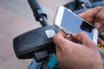 Close-up of hands taking a public scooter with a mobile application