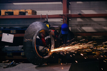 Male worker grinding steel spare part in metalworking workshop