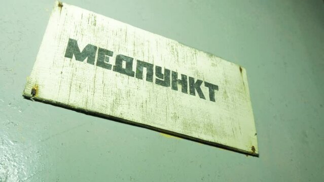 Medical office sign (in russiant) inside the abandoned Soviet underground bomb shelter, old Soviet Cold war bunker, apocalypse, handheld medium close up shot