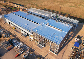 Warehouse Construction from metal structure. Industrial building on light gauge steel framing. Frame of modern hangar or factory. Construction site with steel structure warehouse. Top view on a roof.