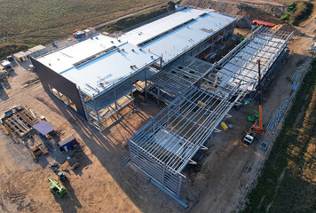 Warehouse Construction from metal structure. Industrial building on light gauge steel framing. Frame of modern hangar or factory. Construction site with steel structure warehouse. Top view on a roof.