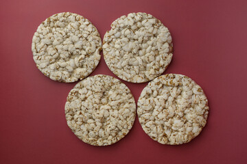 Rice buckwheat crispbread on an isolated background of Bordeaux color (Red-burgundy) top view