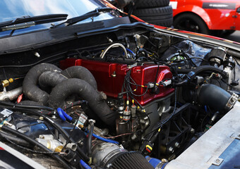 Fototapeta premium Sports car engine with turbine. An open race car hood on a pit stop while racing on a race track. Motor with turbocharger. Boos and tunning.