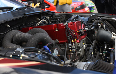 Sports car engine with turbine. An open race car hood on a pit stop while racing on a race track....